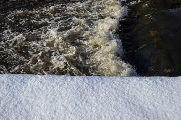 River landscape. Flowing water and snow. Natural winter background pattern