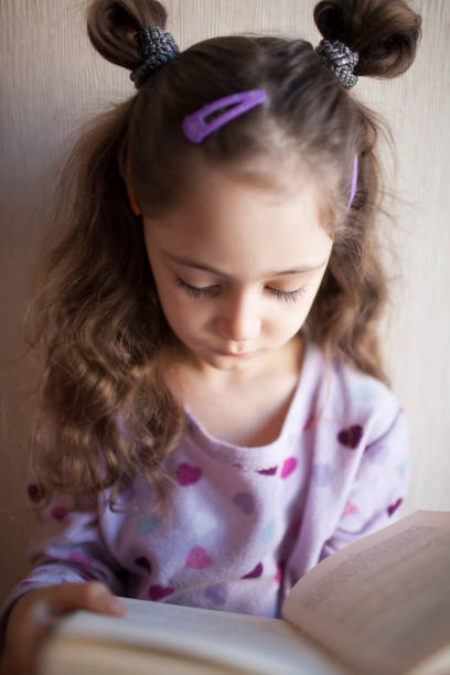 istock Little girl reading a book with interest 1083757700