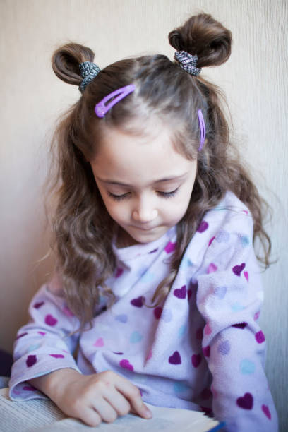 istock Little girl reading a book with interest 1083757820