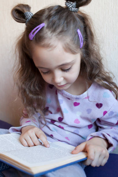 istock Little girl reading a book with interest 1083757852