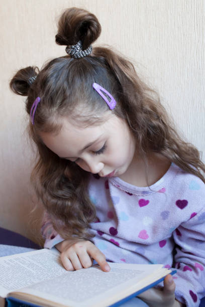 istock Little girl reading a book with interest 1083757896