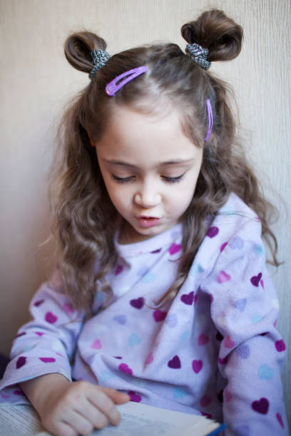 istock Little girl reading a book with interest 1083757906