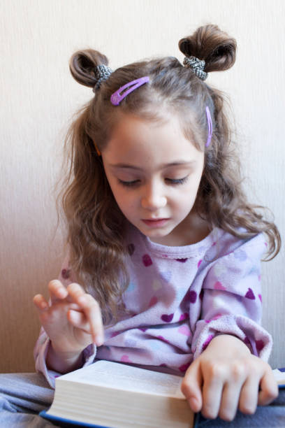 istock Little girl reading a book with interest 1083757956