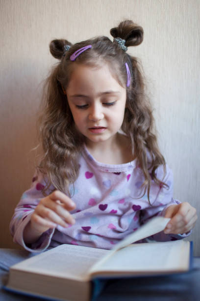 istock Little girl reading a book with interest 1083758054