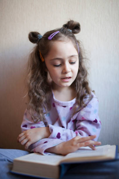 istock Little girl reading a book with interest 1083758058