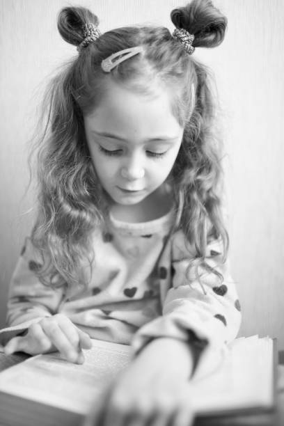istock Little girl reading a book with interest 1083758124