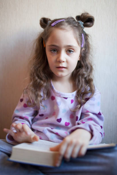 istock Little girl reading a book with interest 1083758156