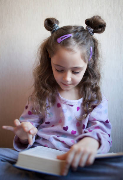 istock Little girl reading a book with interest 1083758220