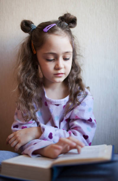 istock Little girl reading a book with interest 1083758494
