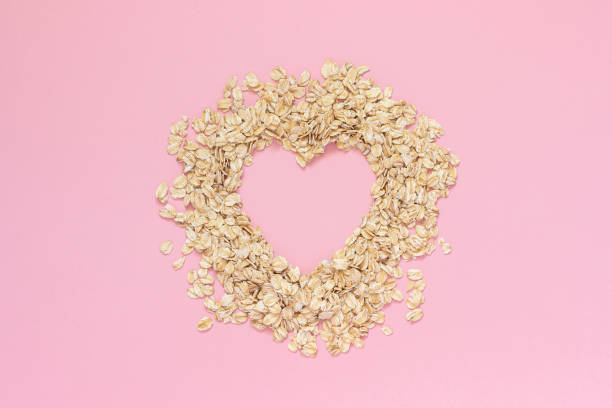 Oatmeal in shape of heart with empty space for text on pink background. Diet concept, Top view Copy space stock photo