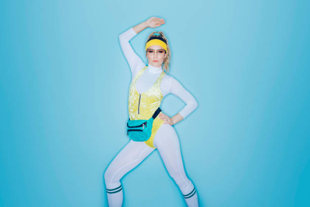 Retro Style Exercise Aerobics Woman Eighties Era A woman wearing exercise clothing styled after the 1980's and 1990's does aerobics style exercises in front of a large bright blue background. 80s aerobics stock pictures, royalty-free photos & images
