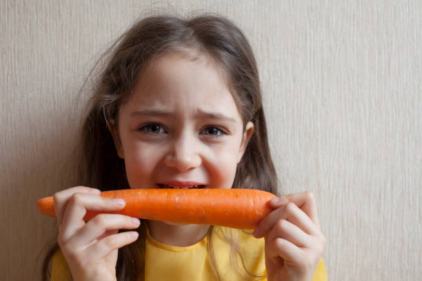 istock Little girl eating carrot 1083768976