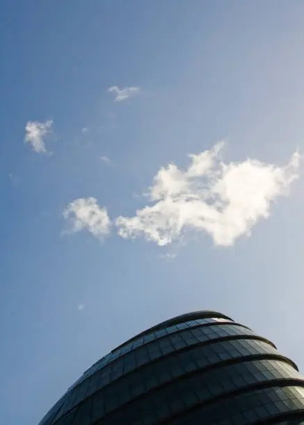 Photo of Small cloud over roof of City Hall, headquarters of Mayor, designed by Norman Foster. Example of modern architecture in UK capital