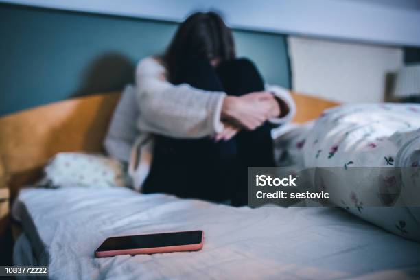 Sad Teen With A Phone In Her Bedroom Stock Photo - Download Image Now - Cyberbullying, Teenager, Depression - Sadness