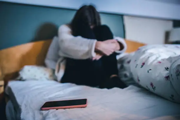 Photo of Sad teen with a phone in her bedroom