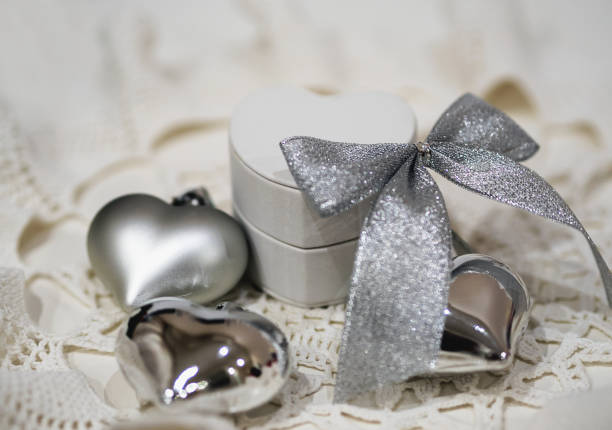 istock White gift small  box with Christmas decorations  on white lace knitted napkin. Selective focus on silver bow 1083772490