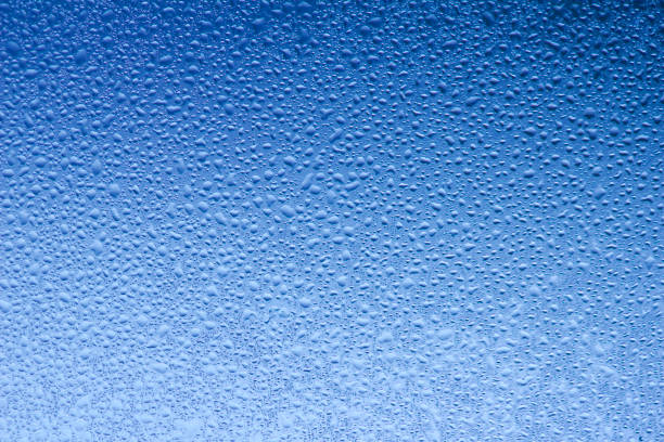 This macro abstract background features a blue hued design of moisture condensation on a flat window pane.