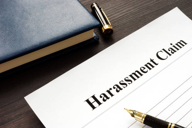 istock Harassment Claim and pen on a wooden desk. 1083774848