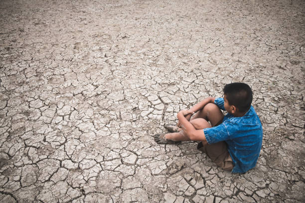 istock Rear View Of Boy Sitting On Drought Land 1083774954
