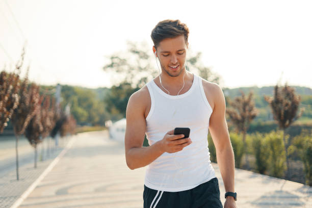 istock Young handsome runner with smart phone and earphones outside 1083775080
