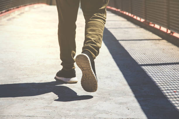 istock Low Section Of Man Walking On Footpath 1083782498