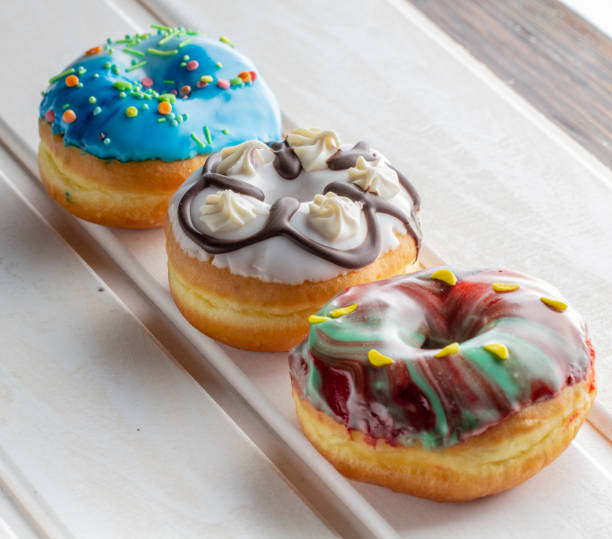 istock Fresh donut poured with icing and decorations, on a white wooden table 1083784614