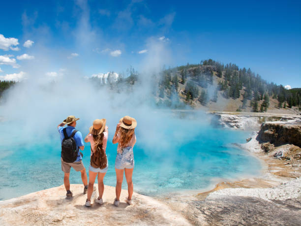 Family relaxing and enjoying beautiful view on vacation hiking trip. Family relaxing and enjoying beautiful view of gazer on vacation hiking trip. Friends on hiking trip. Excelsior Geyser from the Midway Basin in Yellowstone National Park. Wyoming, USA midway geyser basin photos stock pictures, royalty-free photos & images