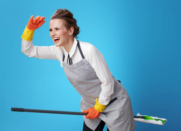 istock smiling young scrubwoman using mop as broomstick on blue 1083796568