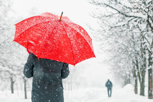 istock Woman with red umbrella standing in snow 1083798730