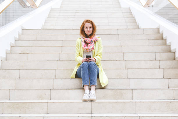 istock Woman sitting on the stairs and using her smartphone 1083800002