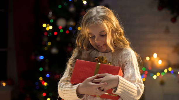 istock Excited blond girl holding long awaited present, magic Christmas atmosphere 1083803514
