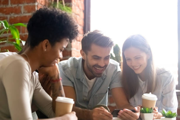 istock Happy diverse friends using phone together in cafe 1083813276