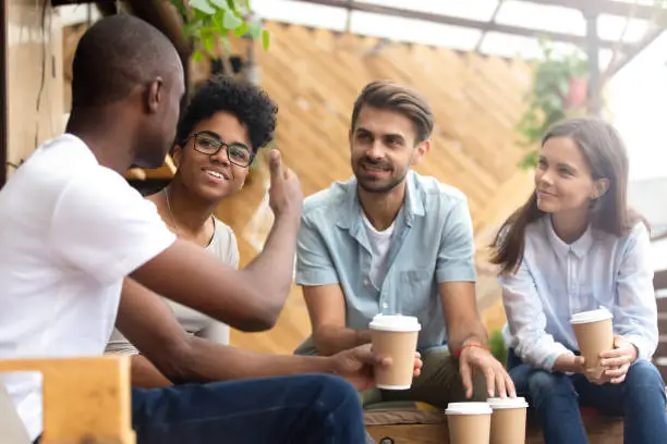 Photo of African American man showing thumb up to friends in cafe