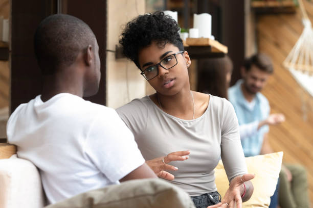 Serious African American woman talking with man in cafe Focused African American woman talking with man in cafe, girlfriend discussing relationships with boyfriend, explaining, gesticulating, friends having serious conversation, sitting together on couch serious talk stock pictures, royalty-free photos & images