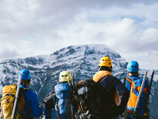 il gruppo di alpinisti sta guardando lo splendido paesaggio in cima alla montagna in inverno - exploration mountain teamwork mountain peak foto e immagini stock