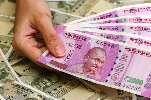 istock Woman's hands holding brand new indian 2000 rupees banknotes. 500 rupee banknotes in background. 1083820976