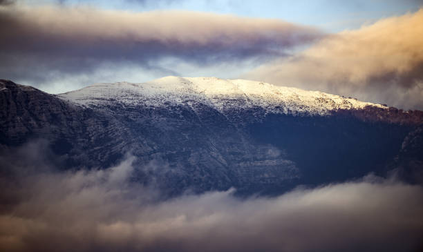 istock Beautiful view of some snowy mountains surrounded by soft clouds during sunset. 1083822602