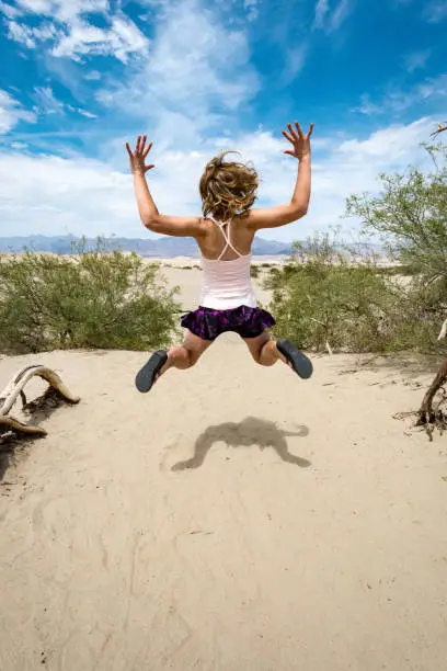 Young adult female woman jumps in the Mesquite Sand Dunes in Death Valley National Park in California