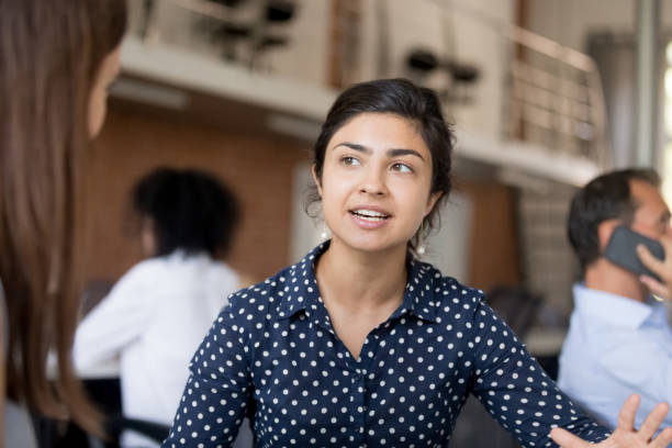 istock Attractive female employee talking with colleague at workplace 1083827580
