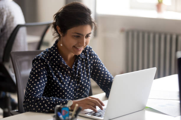 istock Smiling Indian female employee using laptop at workplace 1083827686