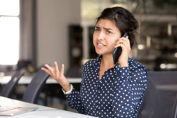 Outraged Indian female employee talking by phone Outraged attractive Indian female employee talking by phone, arguing with client or customer, actively gesticulating, businesswoman having serious conversation on smartphone, solve business problem rudeness stock pictures, royalty-free photos & images