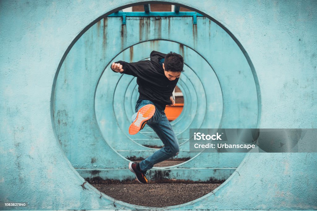 Junge asiatische aktiven Mann in Aktion springen und treten, Kreis Schleife Wand Hintergrund. Extreme sportliche Aktivität, Parkour outdoor freilaufend oder gesunden Lifestyle-Konzept - Lizenzfrei Hochspringen Stock-Foto