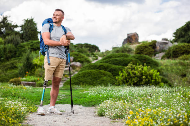 cheerful man with prosthesis standing with nordic walking sticks - aspirations what vacations sport imagens e fotografias de stock