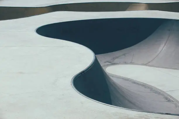 Detail of the shapes of the ramps used as obstacles to make tricks in an empty urban skate park. Useful as a background.