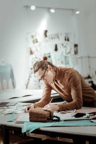 istock Young fair-haired designer from fashion school drawing new models 1083846878