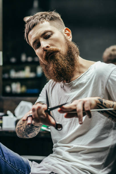 istock Thoughtful barber sitting and touching his scissors 1083853154