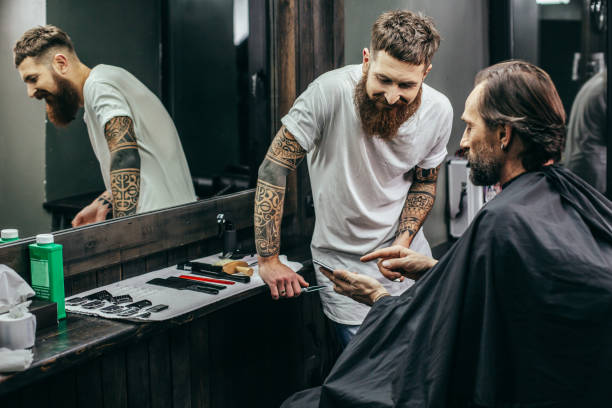 istock Friendly barber smiling while client showing screen of smartphone 1083854362