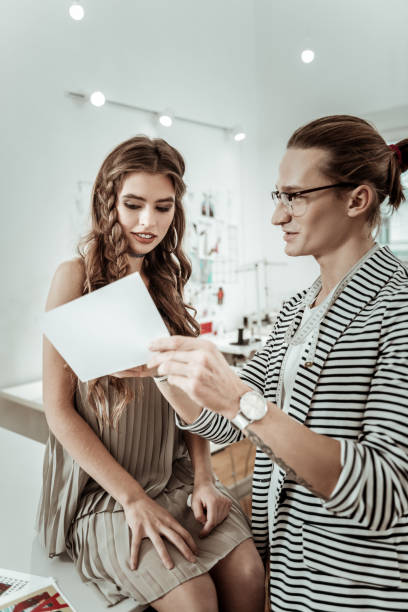 istock Long-haired designer in eyeglasses showing a picture to a beautiful model 1083856030