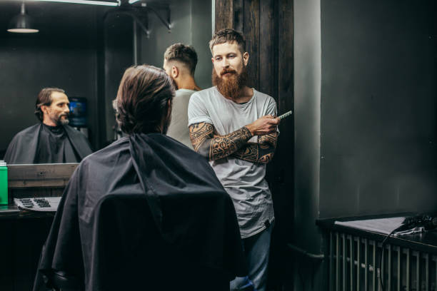 istock Calm barber looking at bearded man and holding comb 1083857024