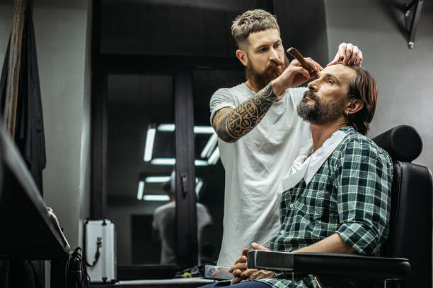 Careful barber standing near the client and using straight razor